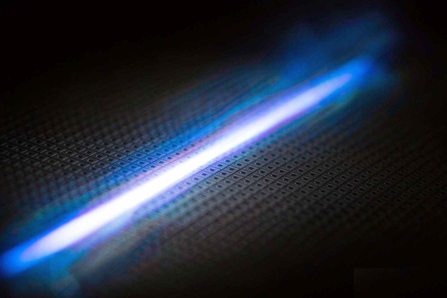 Extreme close-up of a silicon wafer with trails of blue and white light racing across it, suggesting a very large speedup