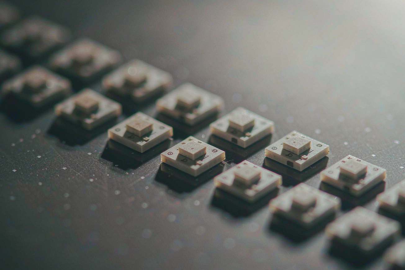 Blank bare silicon dies arranged neatly on a dark surface, repeating geometric structures under cold light