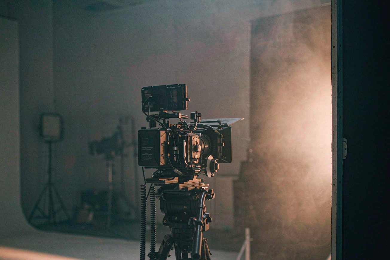 Filmkamera am Set, im Hintergrund ein grauweißes Studio und warmes Licht