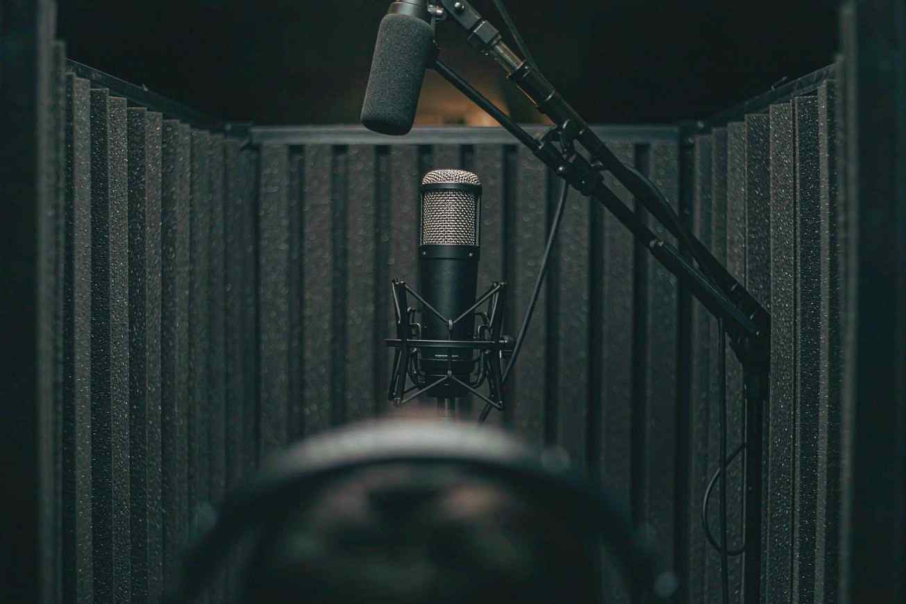 Un microfono a condensatore da studio all'interno di una cabina di registrazione insonorizzata buia