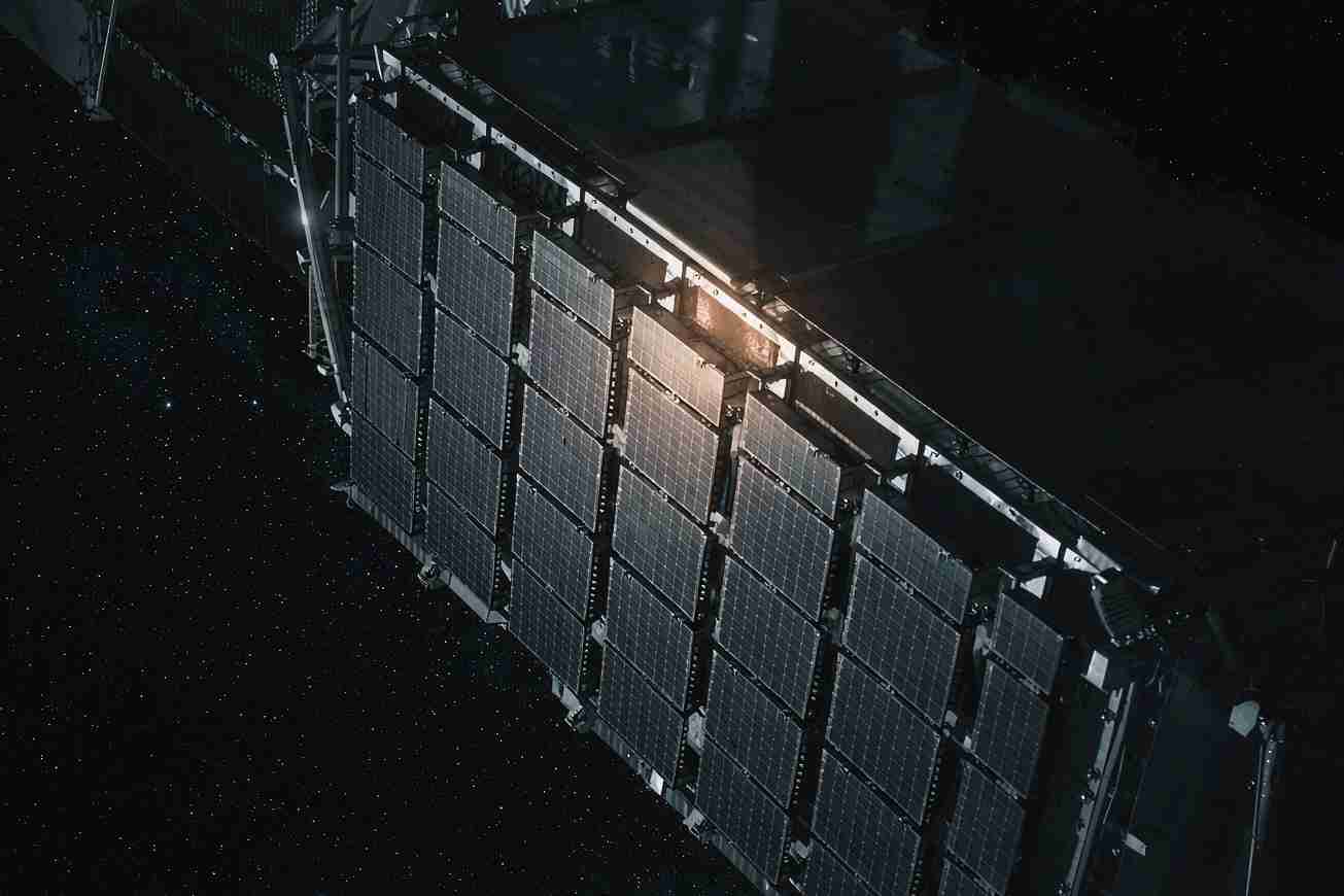 A large dark solar panel array extending from a spacecraft against a star field