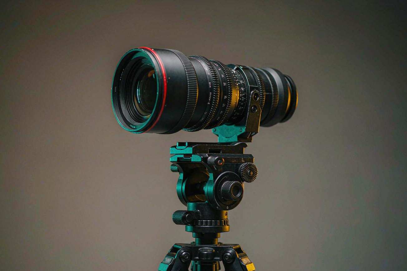 Una lente de cámara de cine sobre un trípode apuntando a un fondo de estudio con iluminación suave