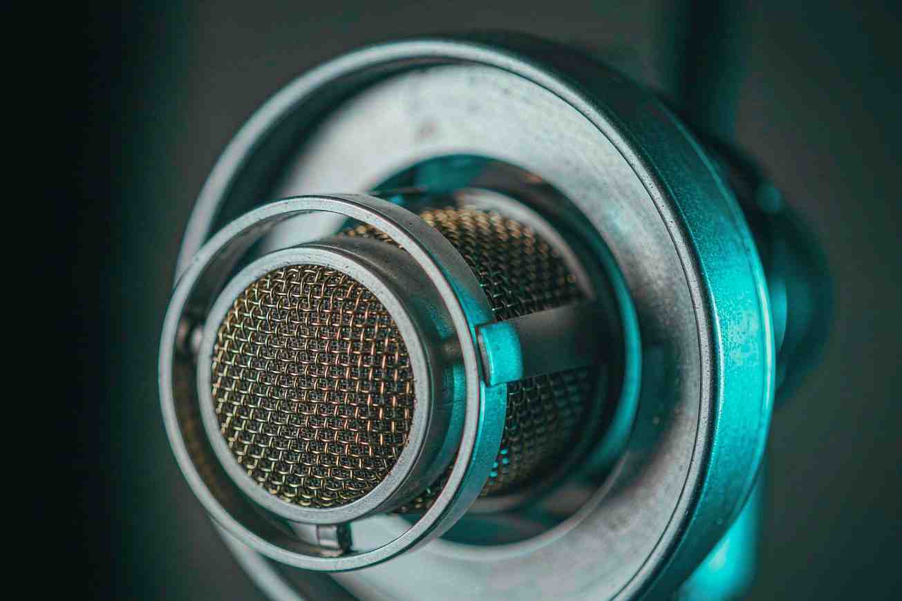 An extreme close up of a microphone diaphragm in fine gold mesh under cyan light