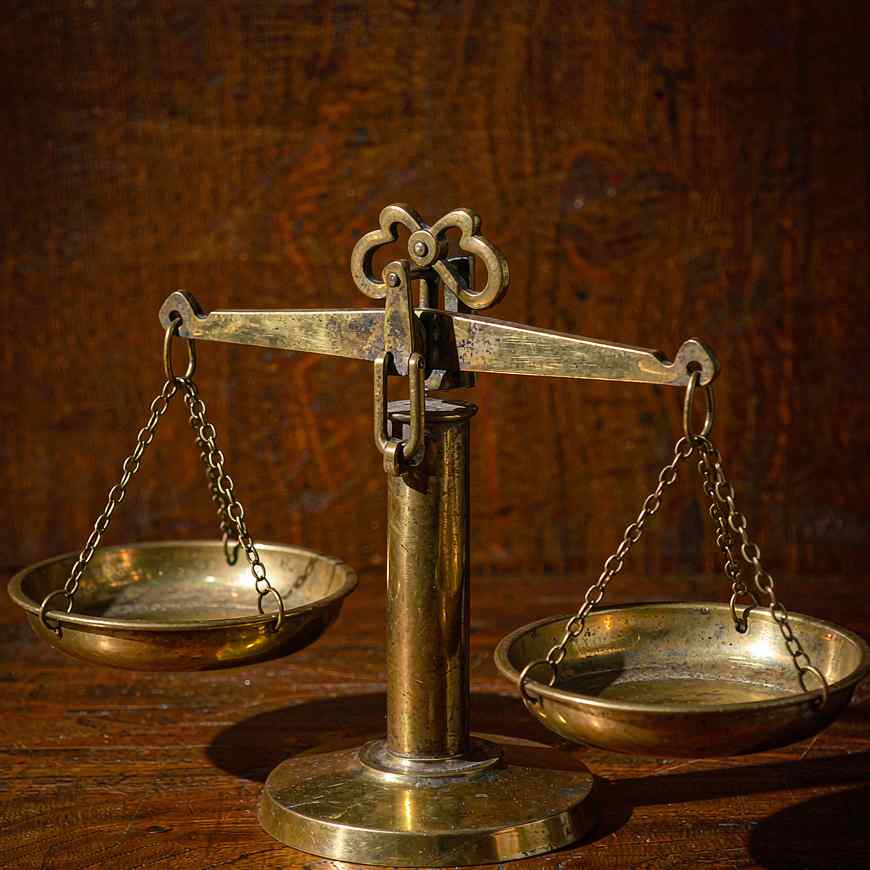 Une balance en laiton poli avec deux plateaux vides sur une table en bois foncé