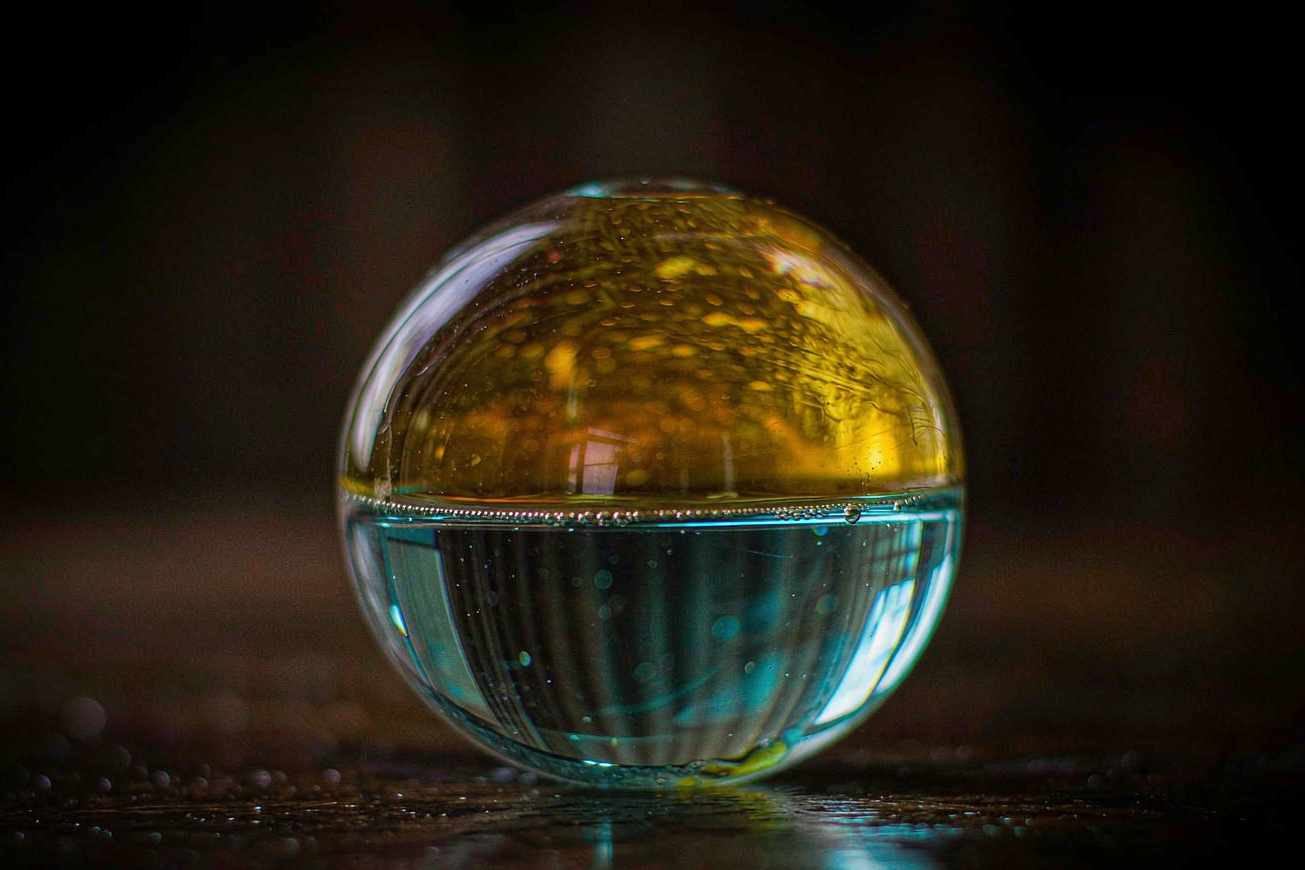 Una sfera di vetro trasparente contenente due scomparti luminosi separati, uno di ambra calda e uno di blu freddo