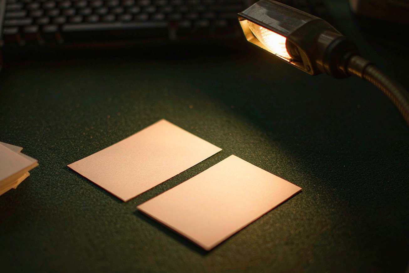 Two blank unmarked ivory cards side by side on dark green felt under a warm lamp
