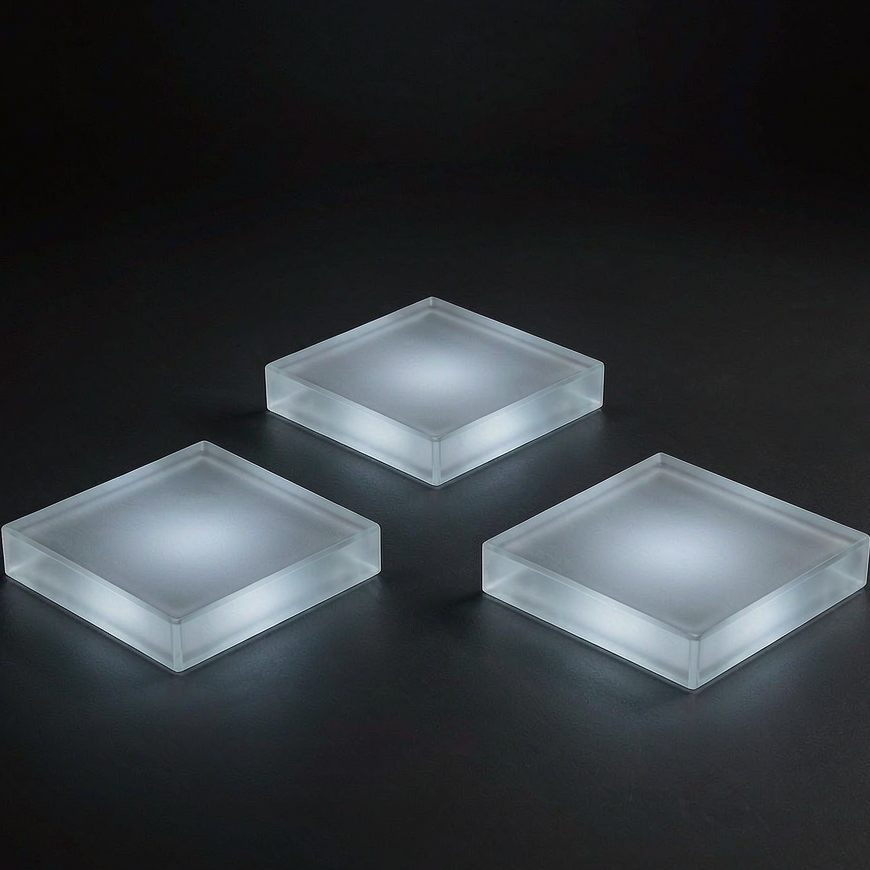 Three blank frosted glass tiles arranged in a loose triangle on a dark matte surface