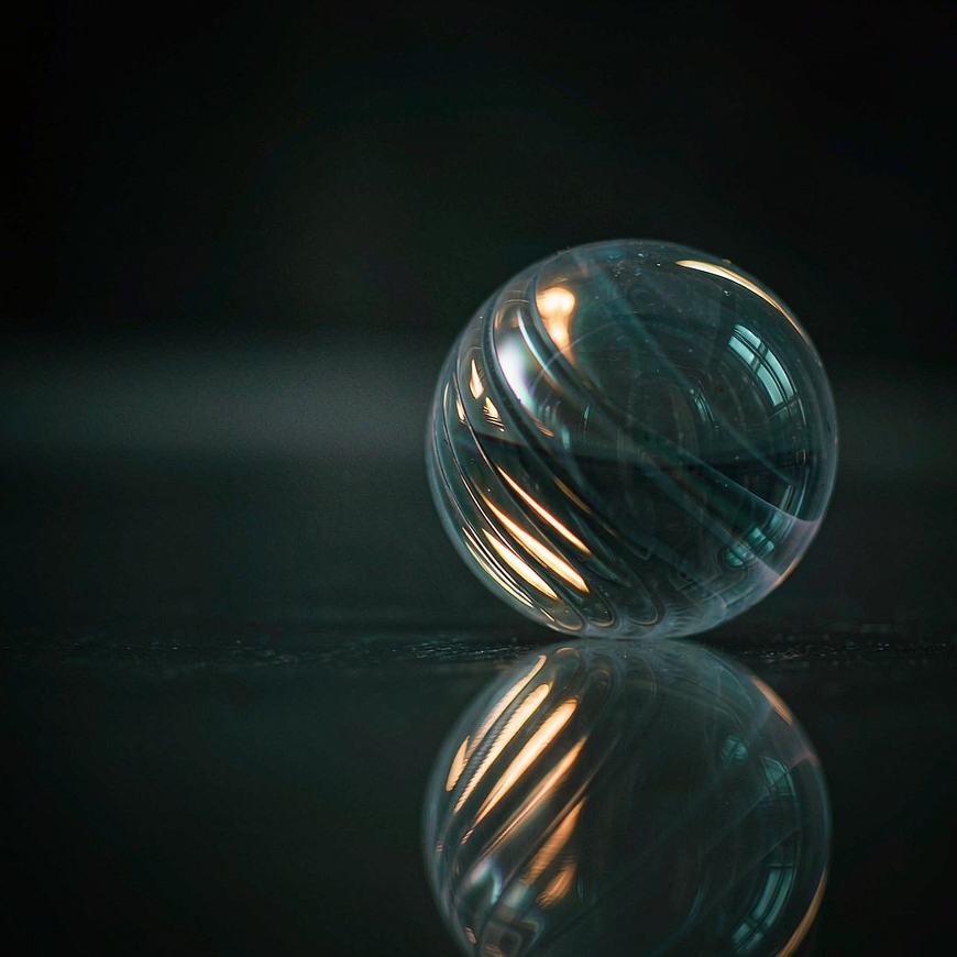 A translucent glass sphere on a dark mirror surface with concentric rings of light