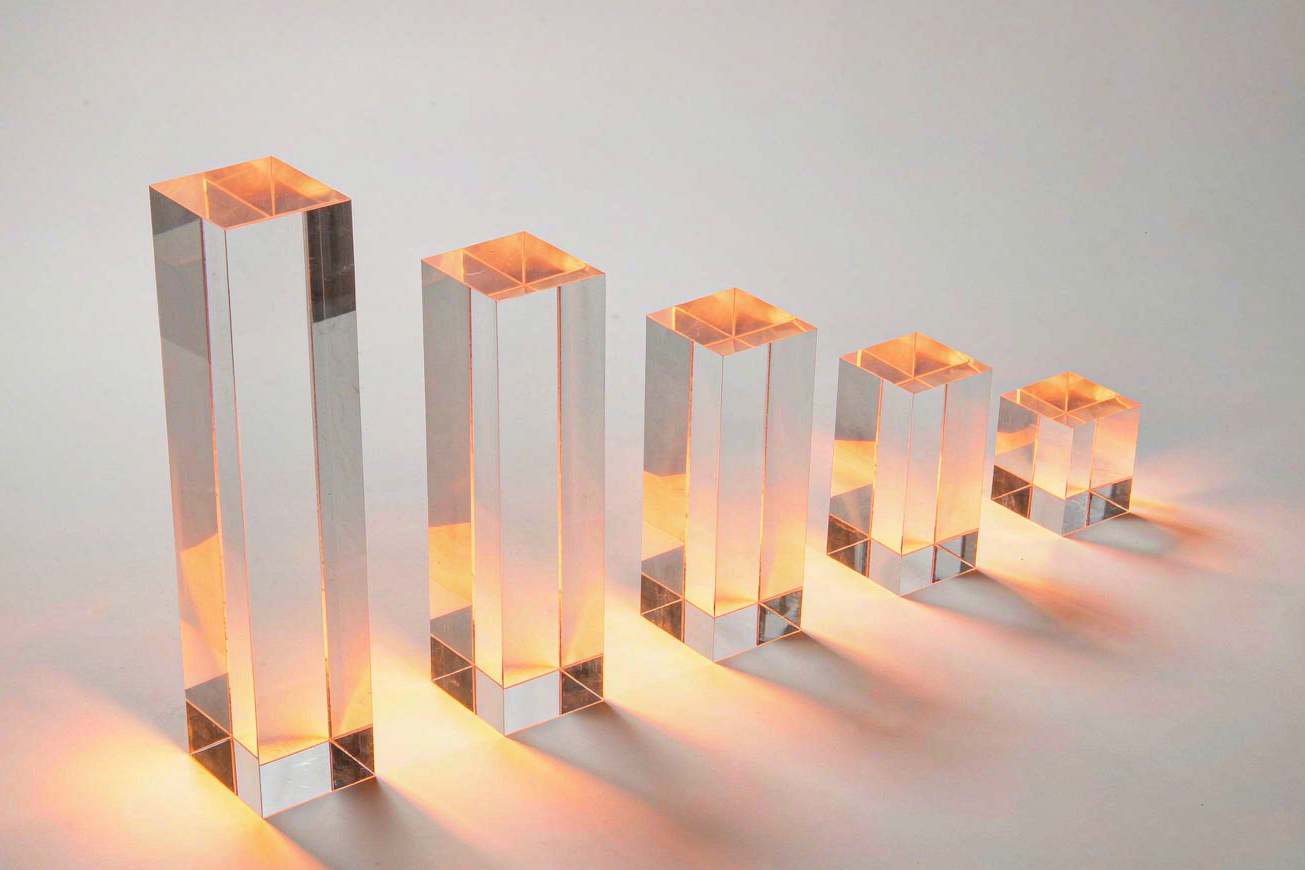 Five translucent acrylic bars of decreasing height in a row, each lit from below with a warm gradient glow