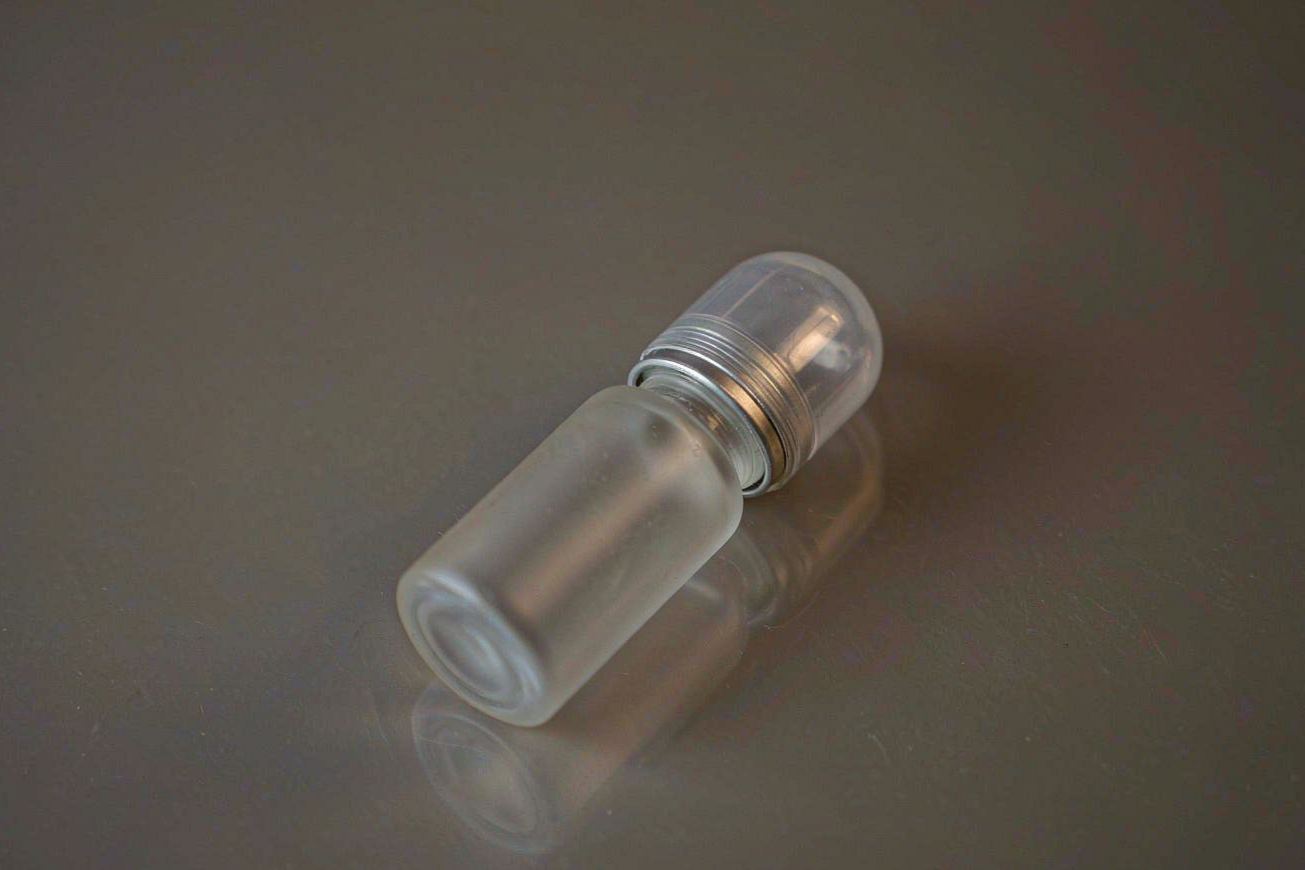 A translucent wax-sealed blank glass vial on a dark surface, the seal catching a warm highlight