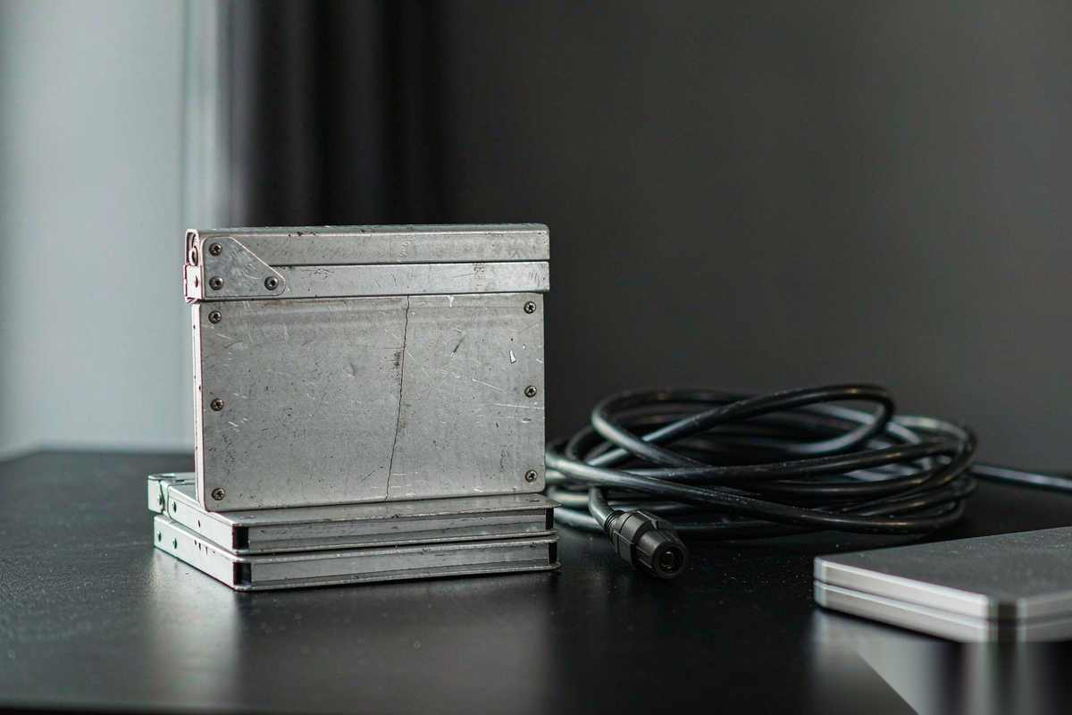A stack of blank film clapperboards on a dark desk beside a coiled cable, the top board cracked