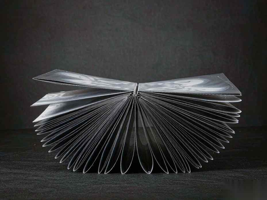 A long corridor of stacked translucent cards receding into darkness, most of them compressed into thin glowing slats while a few near the viewer stay fully open